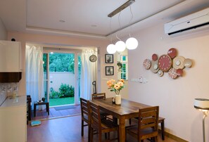 Uma área de refeições com mesa de madeira, cadeiras, um vaso com flores e decorações nas paredes.