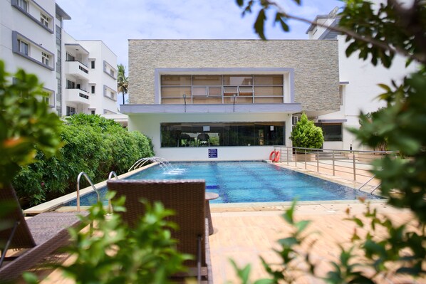 Um edifício moderno com piscina, espreguiçadeiras e vista para a piscina.