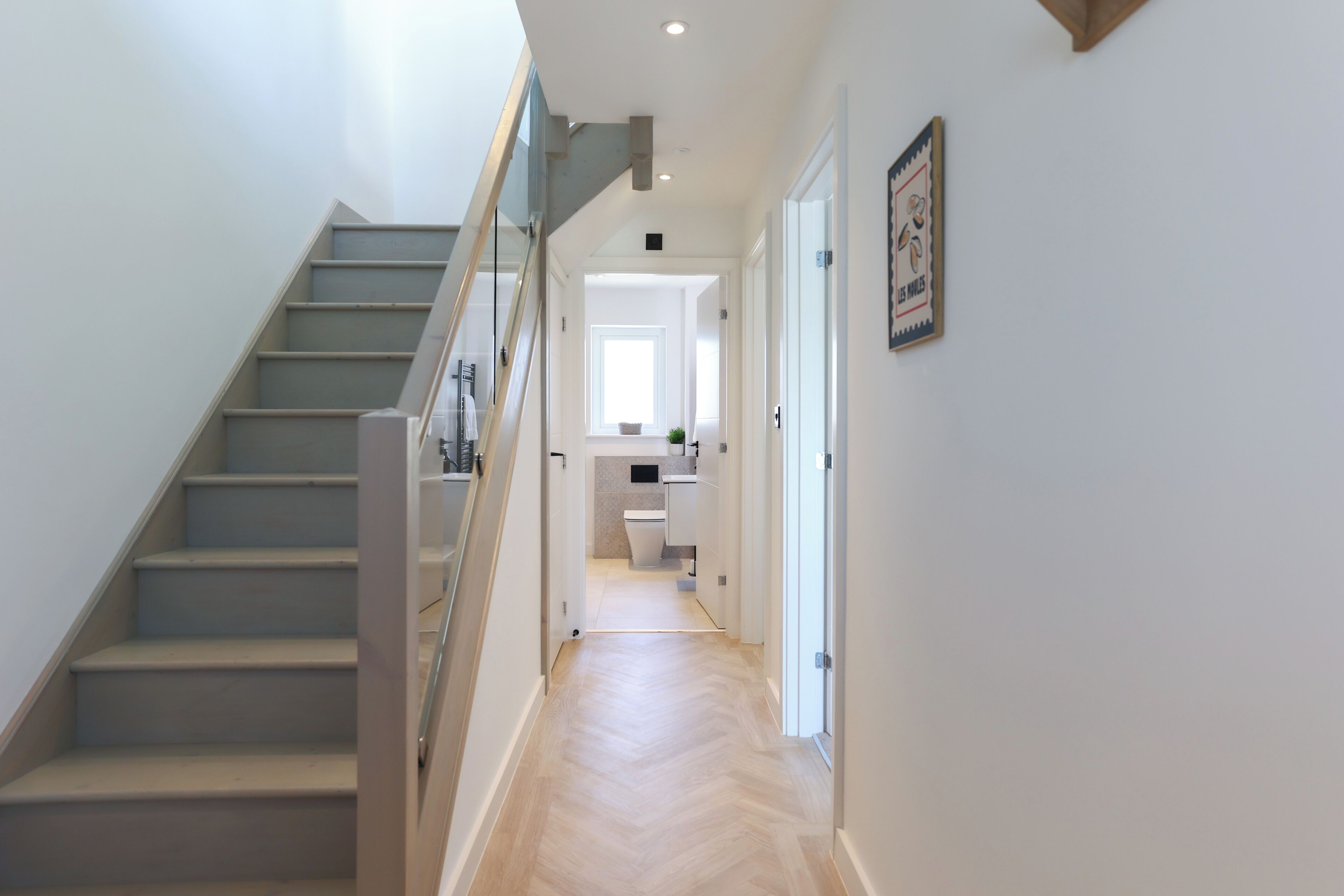 Ein modernes Interieur mit Treppe, einer Küchenzeile und einem Flur zu einer Tür.