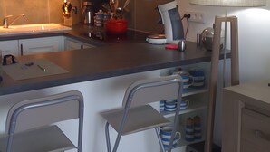 A kitchen with white cabinets, a central island with bar stools, a range hood, and a wall-mounted lamp.