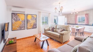 Una sala de estar con un sofá, una mesa de comedor y obras de arte en la pared.