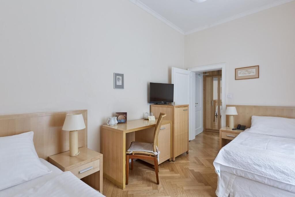 Ein Hotelzimmer mit zwei Betten, einem Schreibtisch mit Stuhl, einem Fernseher und einem kleinen Schrank.
