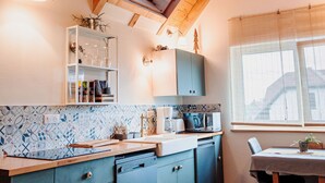 A kitchen with wooden beams, a skylight, a dishwasher, and a dining area with a table and chairs. - NEW ACCOMMODATIONS IN A VILLAGE HOUSE (Orschwiller)