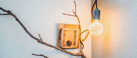 A wall-mounted light fixture with a branch design, a wooden box, and a textured wall.