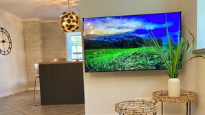 Una cocina moderna con un televisor grande, piso de madera en espiga y un reloj de pared decorativo.