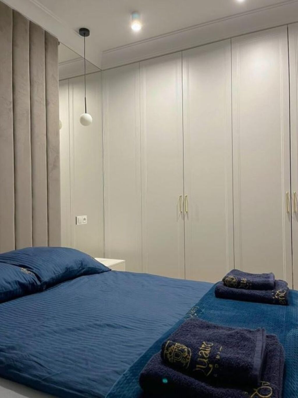 Un dormitorio con una cama, un armario y una lámpara colgante.
