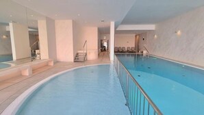 An indoor swimming pool with a clear view of the pool area, a staircase leading to another level, and a seating area with chairs. - Let's Sea SPA - Premium Apartamenty  (Gąski)