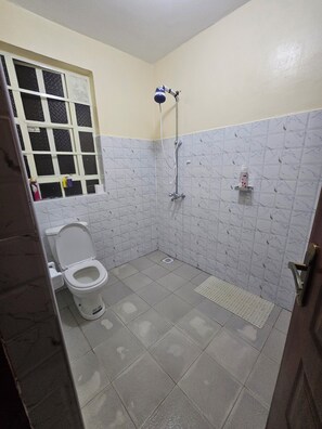 Un baño pequeño con inodoro, ducha y ventana.