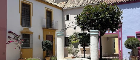 Un cortile con un edificio dotato di tetto in tegole, una piccola fontana e piante in vaso.