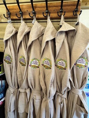 A rack of beige robes with embroidered logos, hanging on a wooden wall. - Posh 3-BDR Home, Beach House - Sleep6 - WiFi - Hot Tub - Free On-Street Parking (Donaghadee)