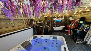 Een jacuzzi met meerdere jets, een houten terras, een barhoek en een ouderwetse badkuip.