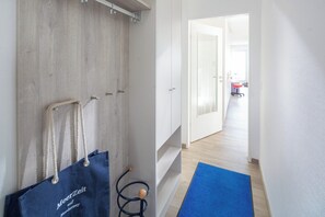 Ein Flur mit einer Holztür, einer blauen Matte und einer blauen Tasche mit Text.