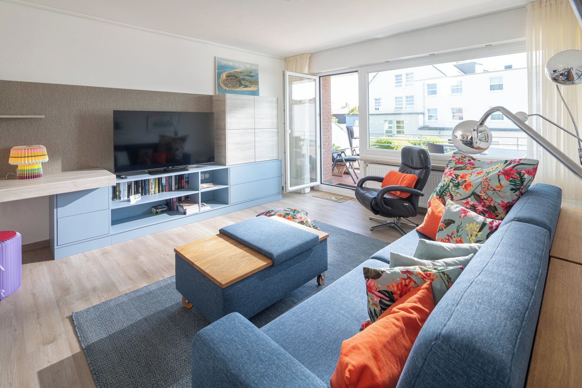 A modern living room with a flat-screen TV, a sofa, a coffee table, and a bookshelf.