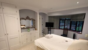 Quarto com cama, televisão, janela e guarda-roupa.