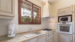 Una cocina equipada con cafetera, lavamanos, estufa, microondas y alacenas.