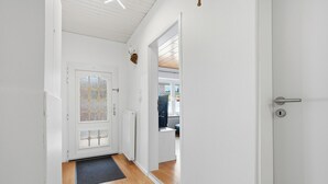 Un couloir avec un plancher en bois, une porte dotée d’un panneau en verre et un radiateur.