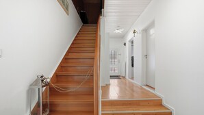 Un escalier en bois menant à un palier avec un mur blanc et une porte.