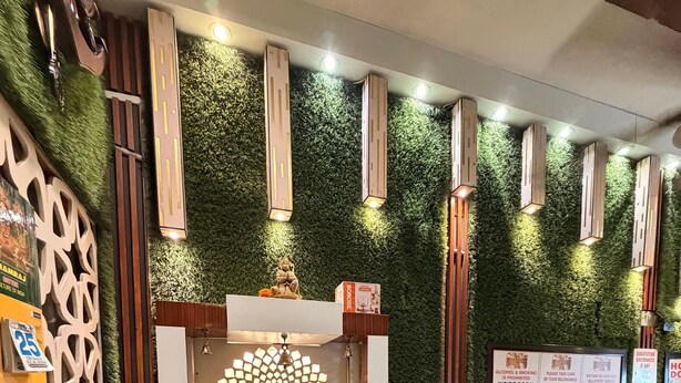 A hotel room with a decorative altar, a refrigerator, and a patterned sofa.