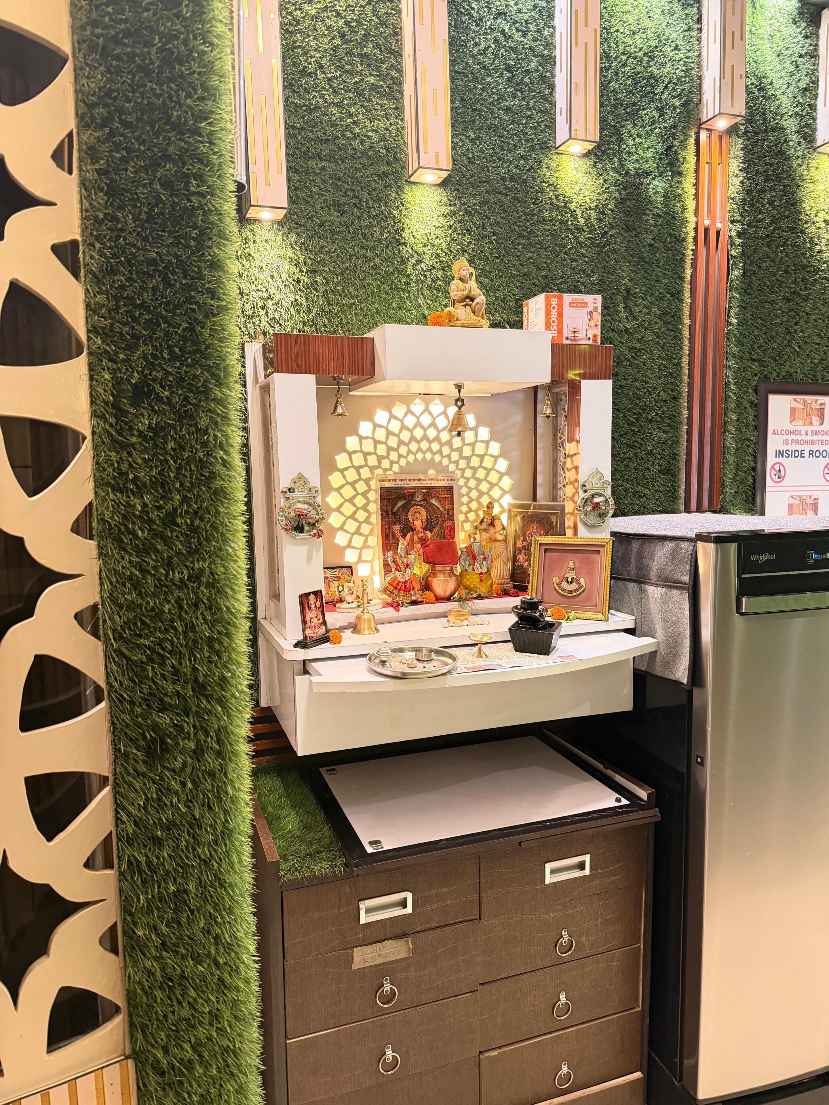 A room with a shrine, a refrigerator, and a wall with vertical light fixtures.