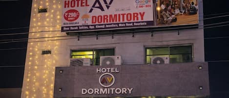 Un hôtel avec une enseigne indiquant qu’il s’agit d’un dortoir, affichant un numéro de téléphone et un prix.