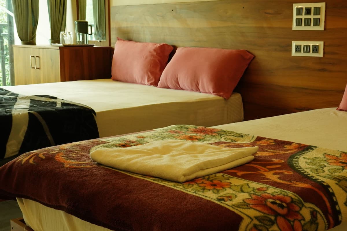 Habitación de hotel con dos camas, cabecero de madera, una mesita con lámpara y ventana con cortinas.