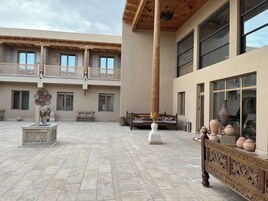 Un patio con suelo de baldosas, una columna central y un balcón con celosía.