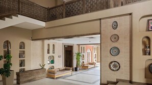 A spacious lobby with a high ceiling, a wooden reception desk, and a seating area with sofas. - Arda Karvon Saroy (Khiva)