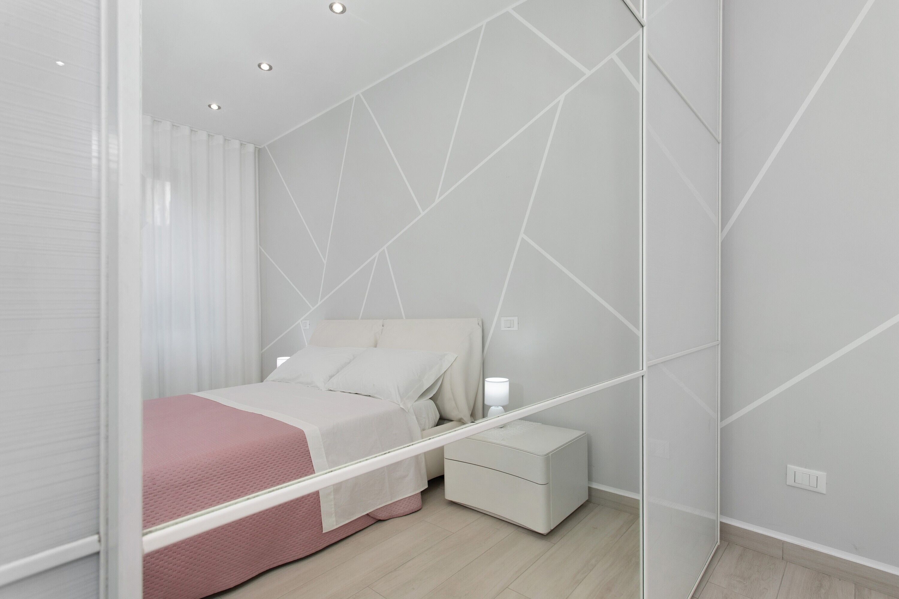 Une chambre à coucher moderne avec un lit, une table de chevet et un miroir.