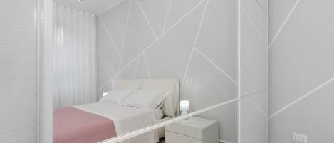 Une chambre à coucher moderne avec un lit, une table de chevet et un miroir.