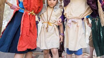 Children in historical costumes examining a pile of green grapes.