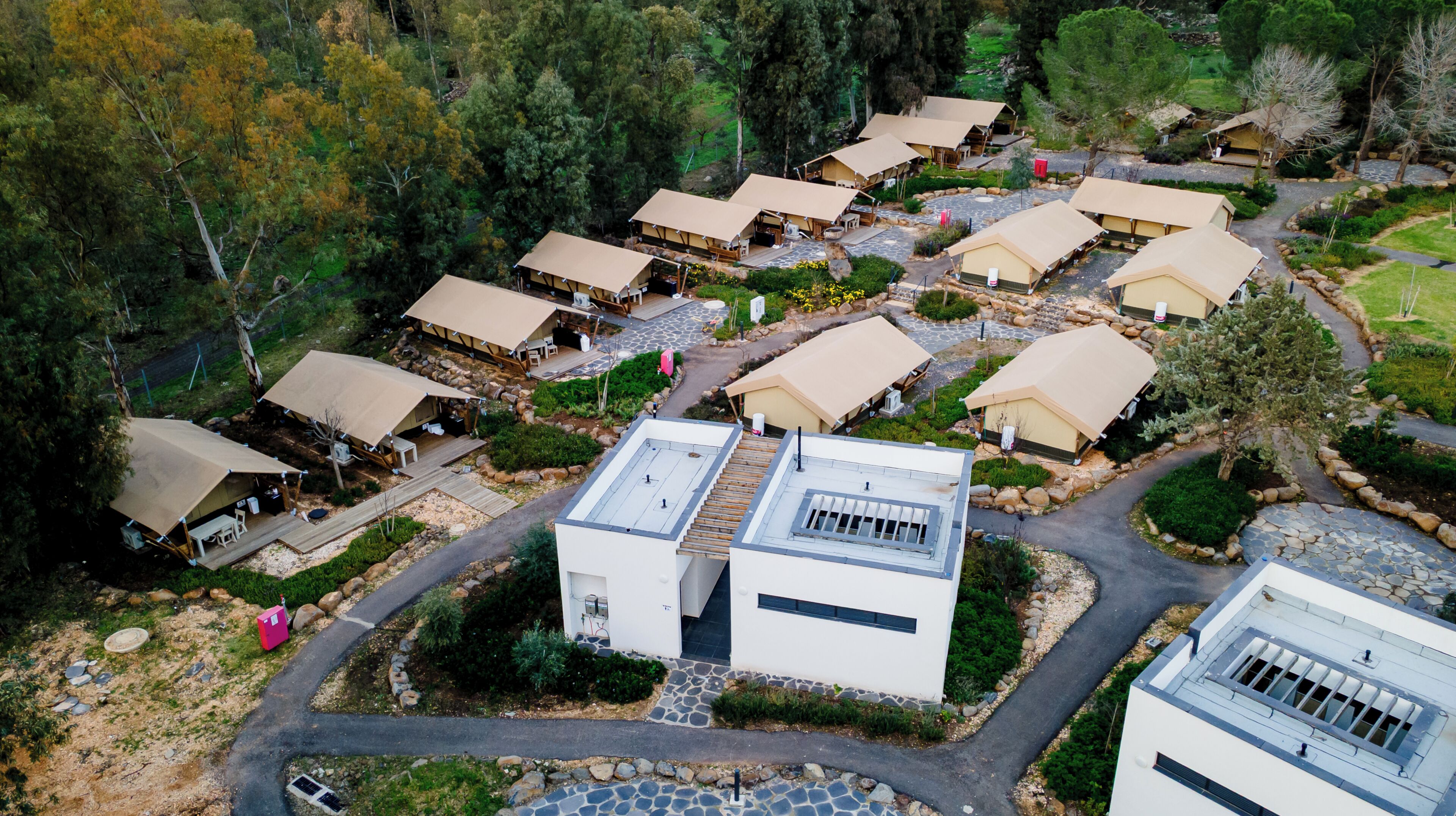 Vista aérea de um resort com diversas acomodações em estilo bungalow, dispostas em um padrão semicircular ao redor de um pátio central.
