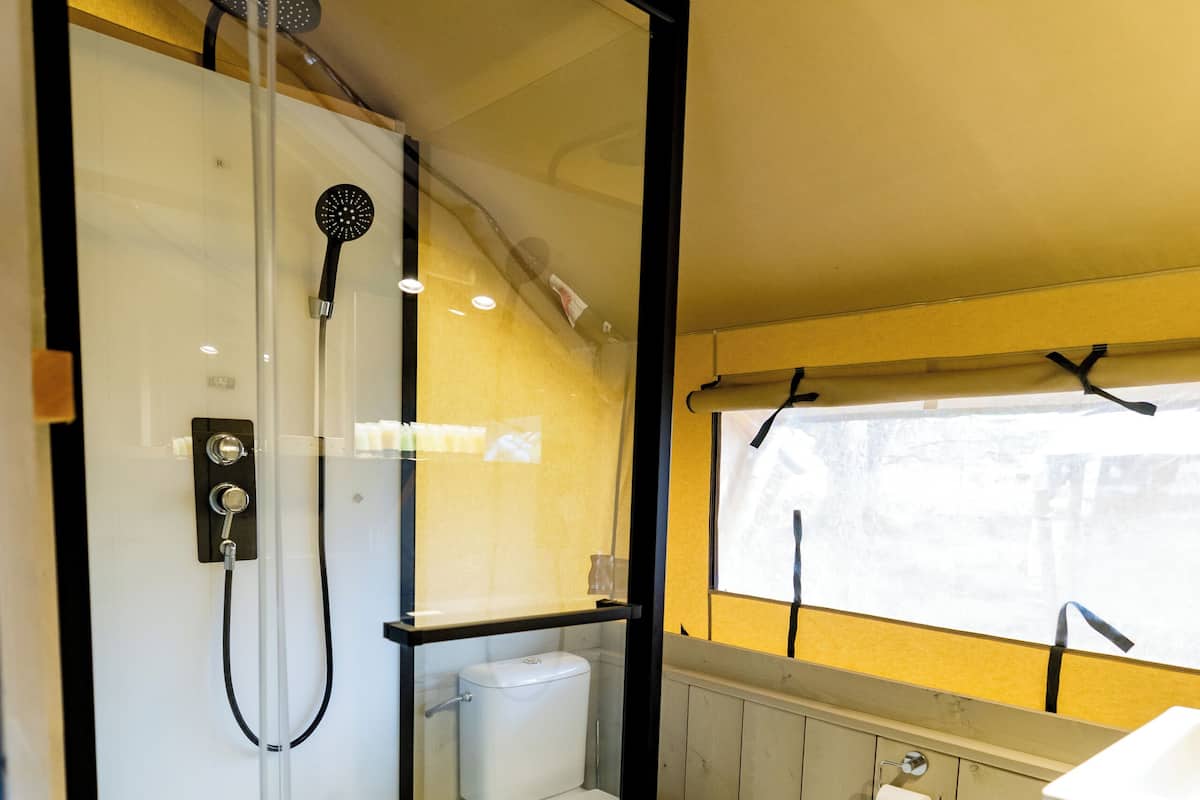 Ett litet badrum med en dusch som är avskärmad med glasväggar, en toalett och ett handfat.