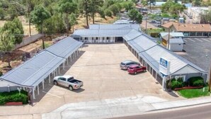 A motel with a parking lot, covered walkways, and a small building with a sign.