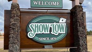 A wooden sign with 'WELCOME' at the top and 'SHOW LOW SINCE 1870' in the center.