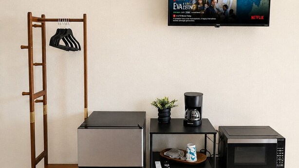 Eine Küchenzeile mit Kühlschrank, Mikrowelle, Kaffeemaschine und einem Fernseher, der einen Filmplakat zeigt.