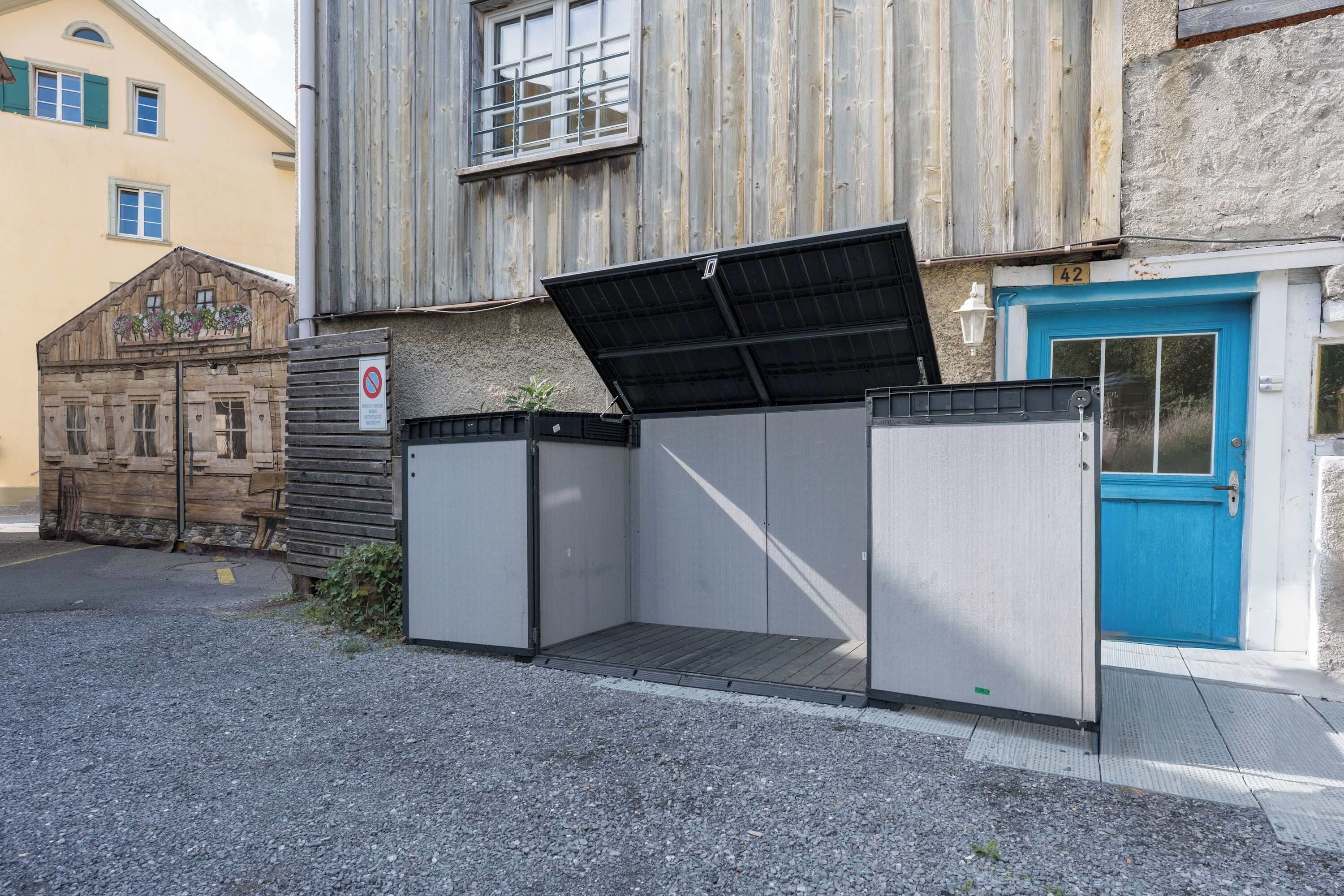 A building with a blue door, a metal fence, and a wooden structure with heart-shaped windows.