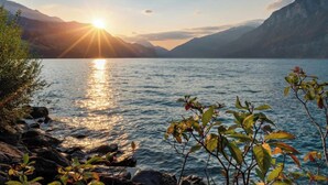 Un lac avec des montagnes en arrière-plan et la lumière du soleil se reflétant sur l’eau.