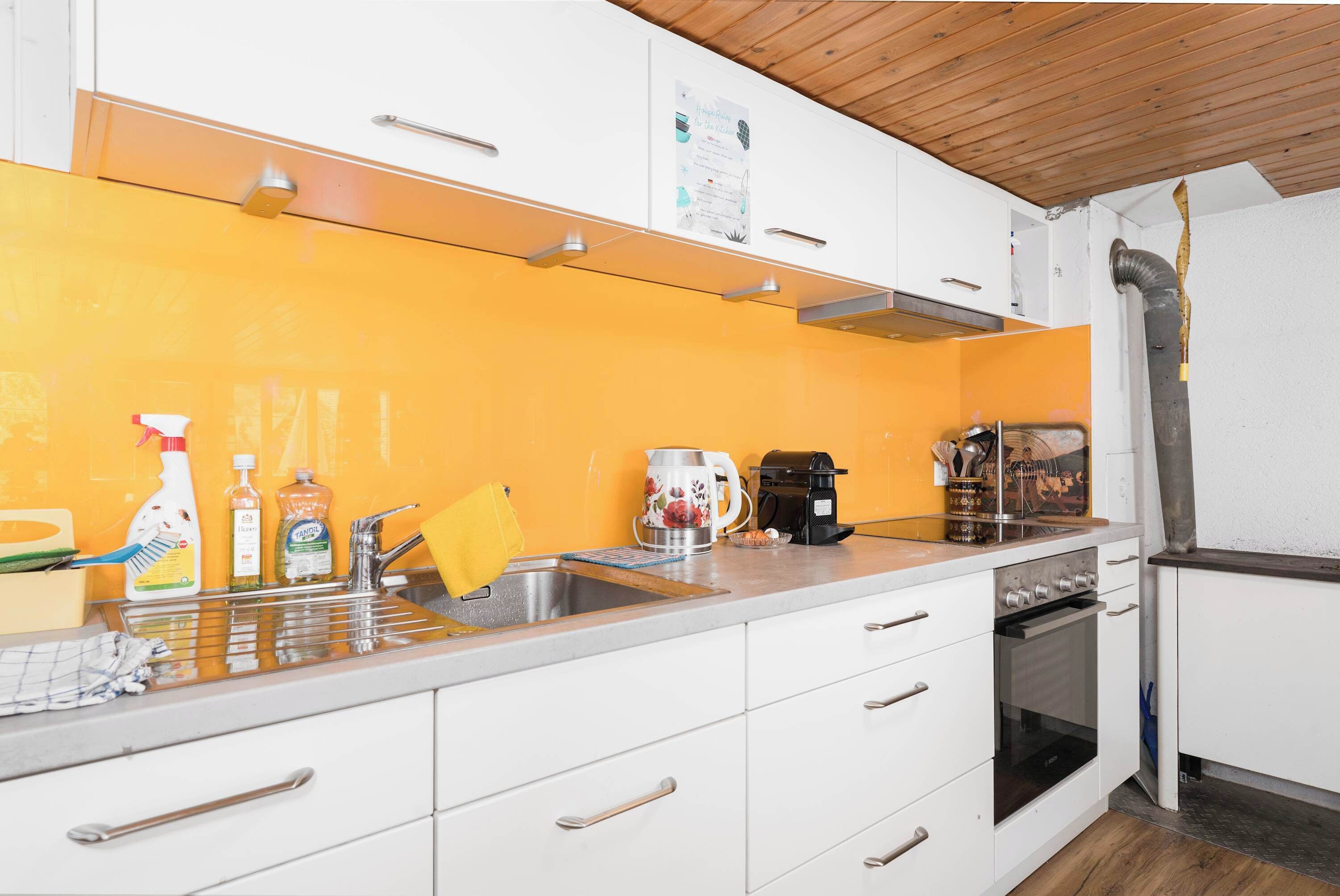 A kitchen with white cabinets, a sink, a coffee maker, and an oven.