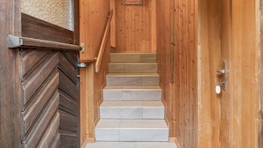 A wooden staircase with a textured wall and a welcome sign.