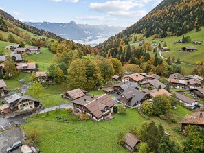 Un borgo montano con case tradizionali, vista libera sulla valle e un lago sullo sfondo.