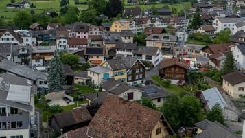 Eine Stadt mit Wohnhäusern, einem markanten gelben Gebäude mit rotem Dach und einem Berg im Hintergrund.