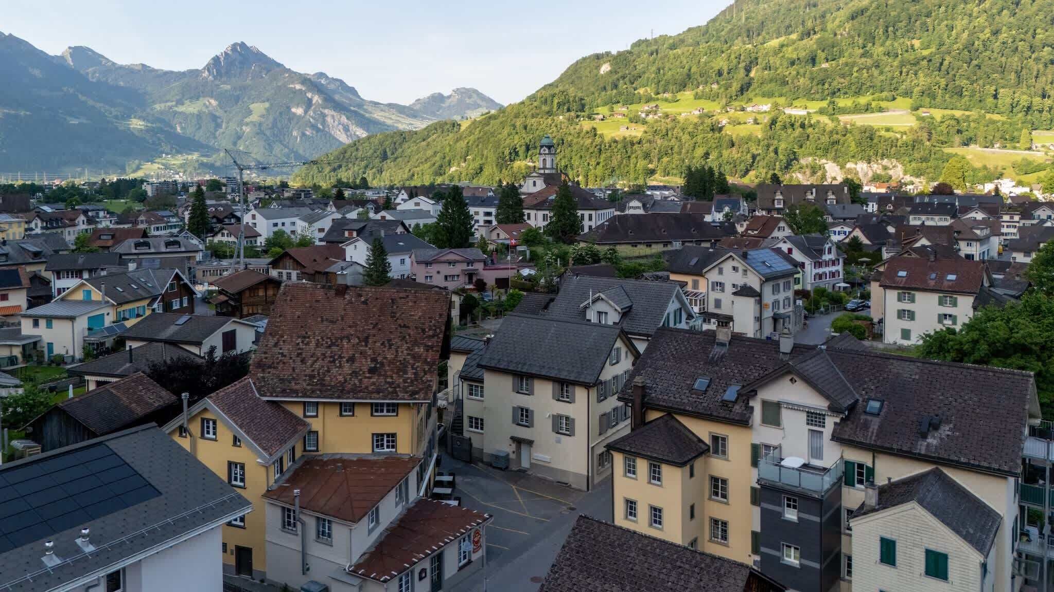 A town with traditional architecture, a prominent church, and a mountain backdrop.