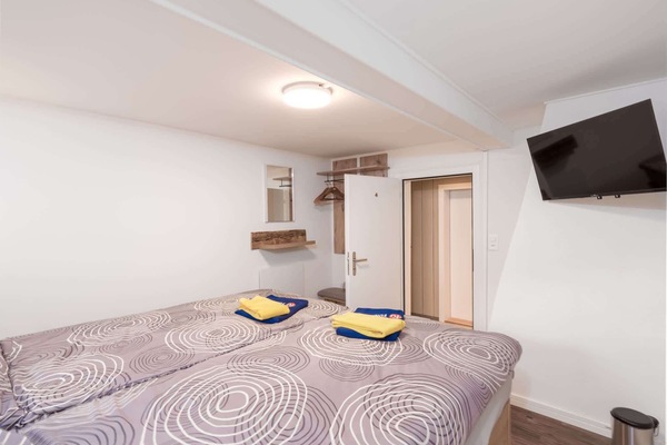 Private double room with TV, double bed, fresh towels, and access to shared bathroom facilities.