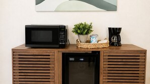 Ein Holzschrank mit einer Mikrowelle, einer Kaffeemaschine und einer kleinen Pflanze.