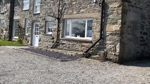 A stone building with multiple windows and a door, likely a residential property. - Scenic Retreat for 8 + Hot Tub with views over lakes, mountains & the sea. (Pentrefelin)