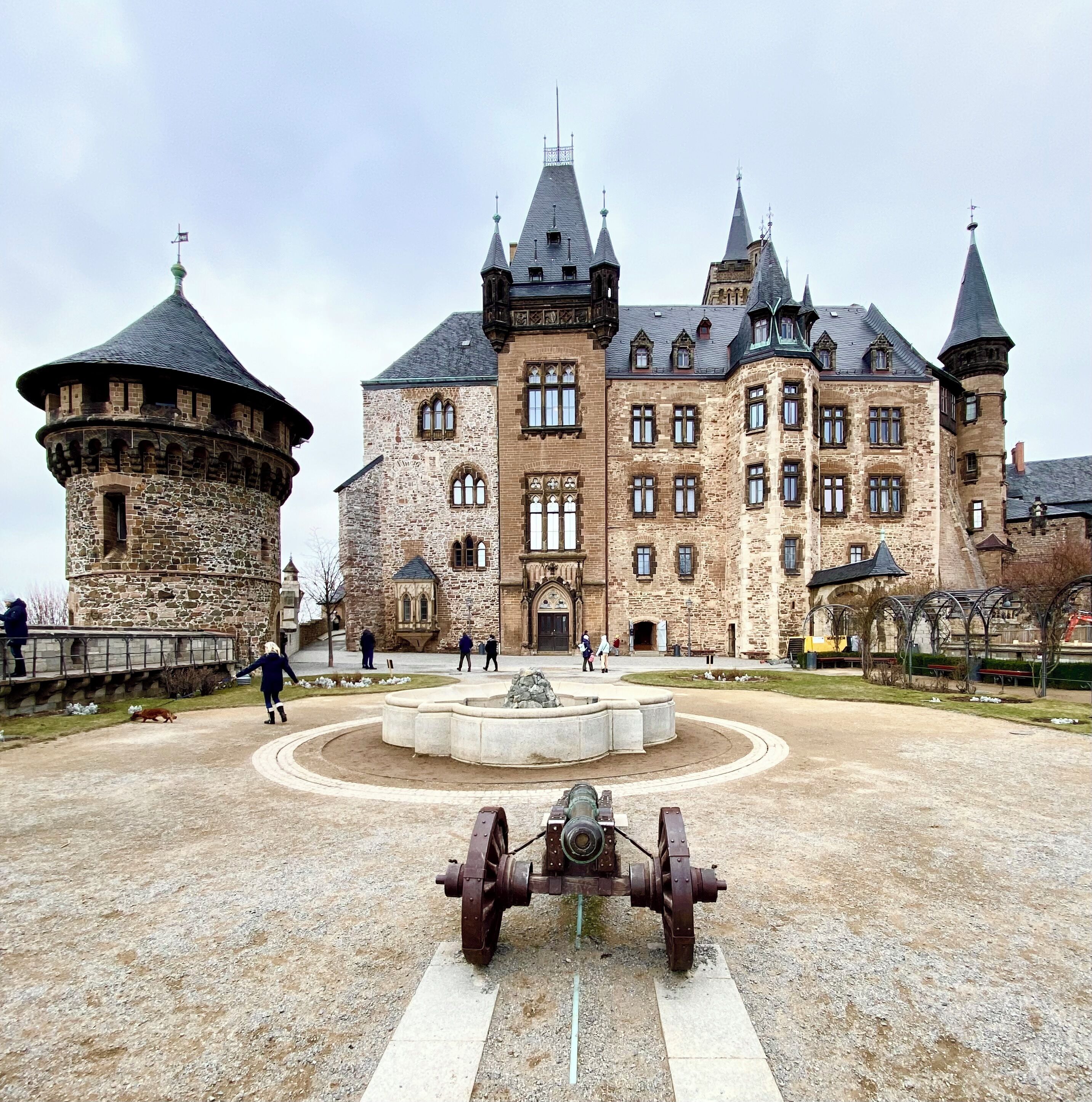 A historic building with multiple towers and a courtyard with a large mechanical structure.