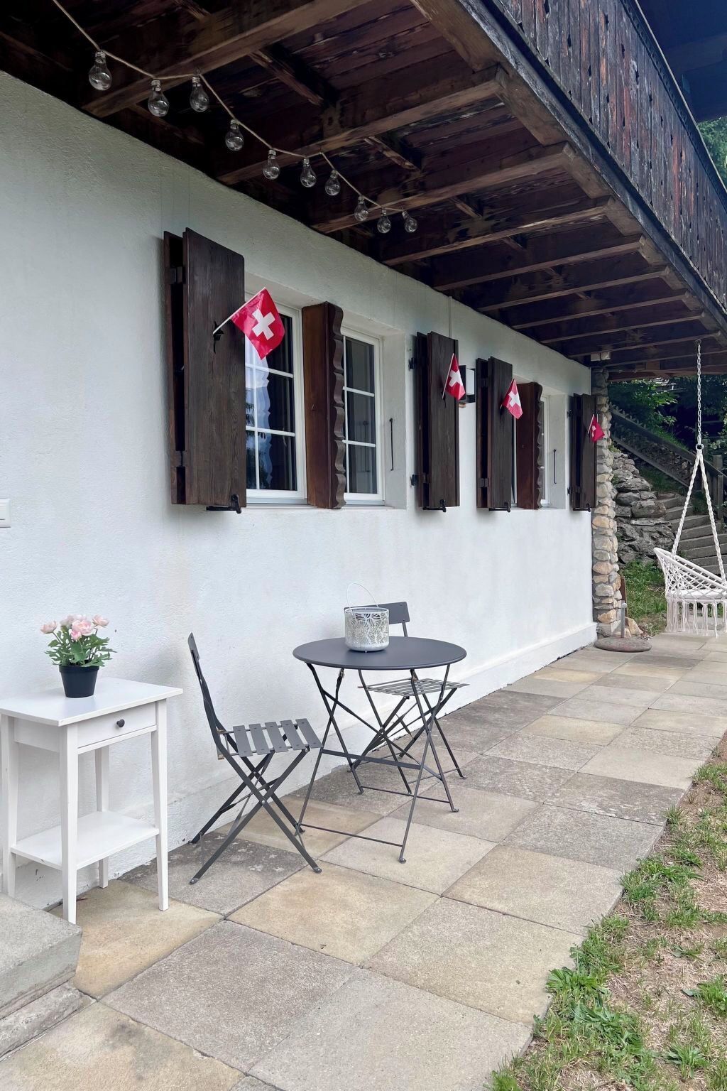 Un portico coperto con tavolo e sedie, un tavolino bianco e una pianta in vaso.