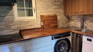 Una cucina compatta con lavatrice e asciugatrice integrate, una finestra con vetro smerigliato e mobili in legno.