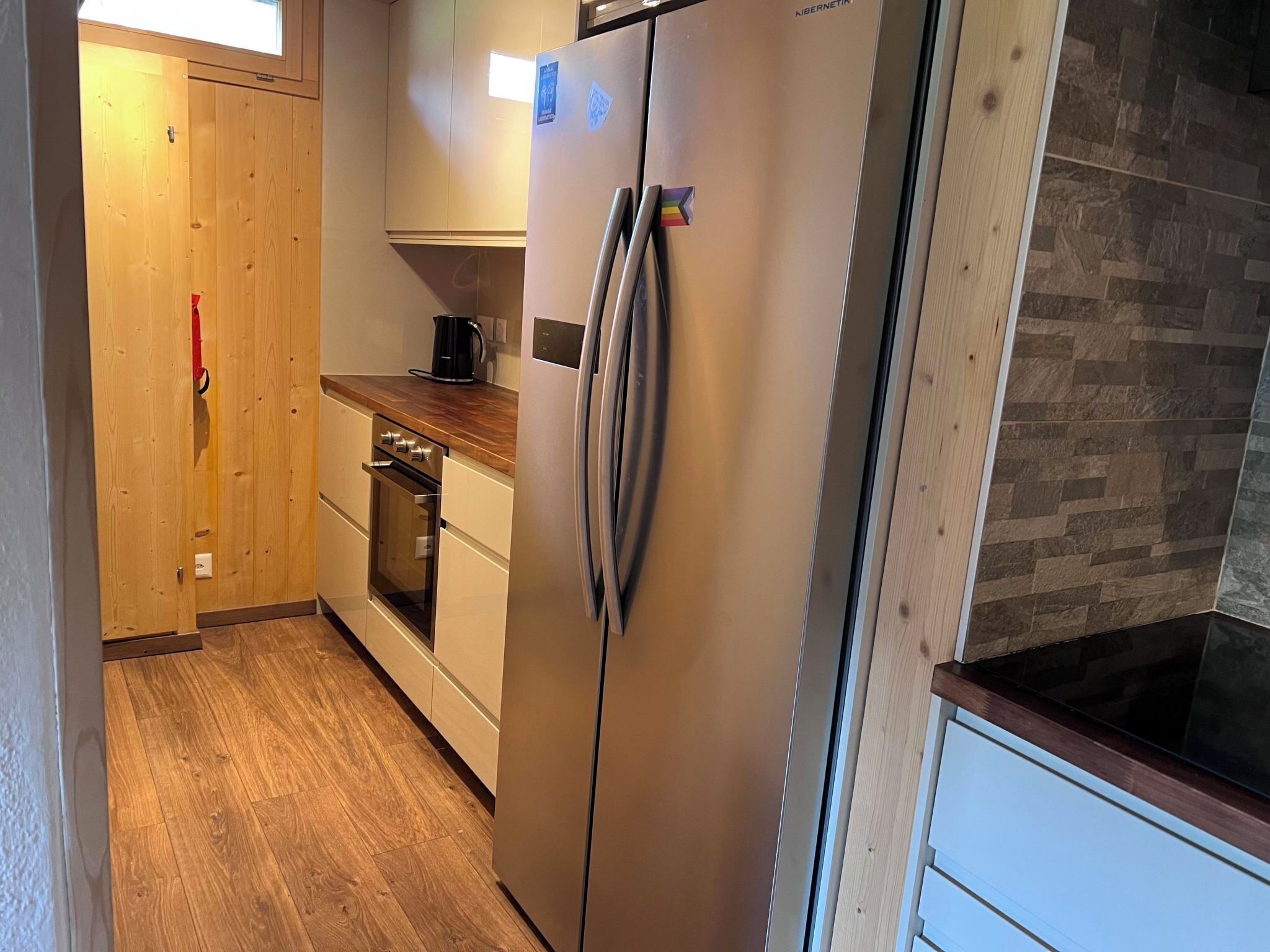 Een keuken met een roestvrijstalen koelkast, houten kastjes, een inbouwoven en een houten aanrecht.