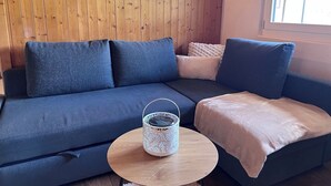 Un soggiorno moderno con un divano blu scuro, un tavolino rotondo in legno e una lanterna bianca decorata.